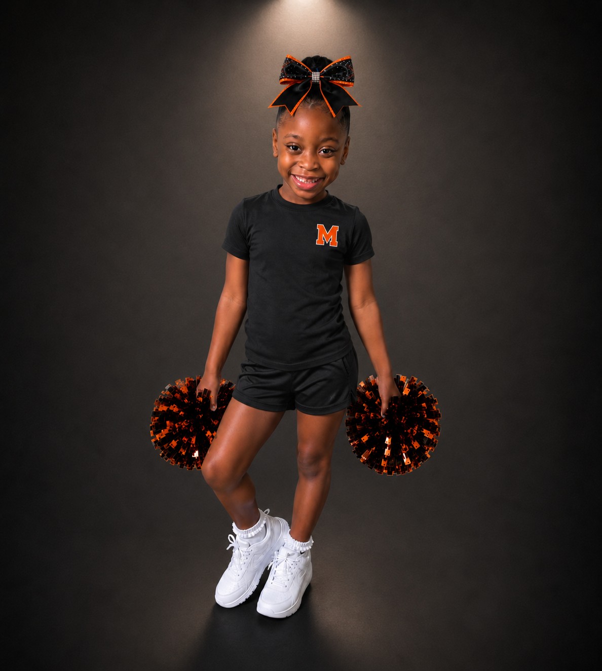 Smiling young Atlanta Monarchs athlete in practice gear holding pom-poms